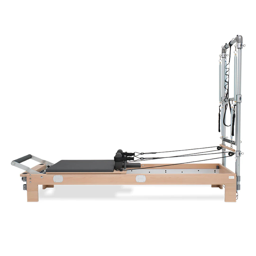 BASI Systems Reformer with Tower featuring adjustable pulleys, cushioned carriage, footbar, and push-through bar for professional Pilates training.