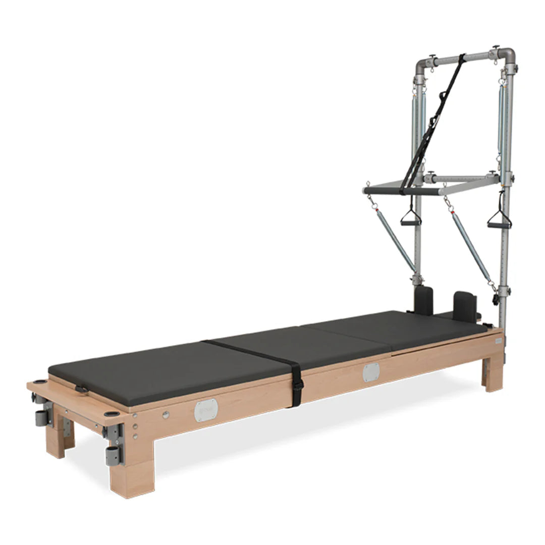 BASI Systems Reformer with Tower featuring adjustable pulleys, cushioned carriage, footbar, and push-through bar for professional Pilates training.