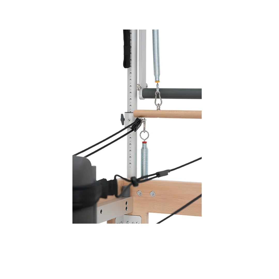 Close-up of the BASI Systems Reformer Combo's spring-loaded pulley system with wooden push-through bar and adjustable tower frame used for Pilates exercises.