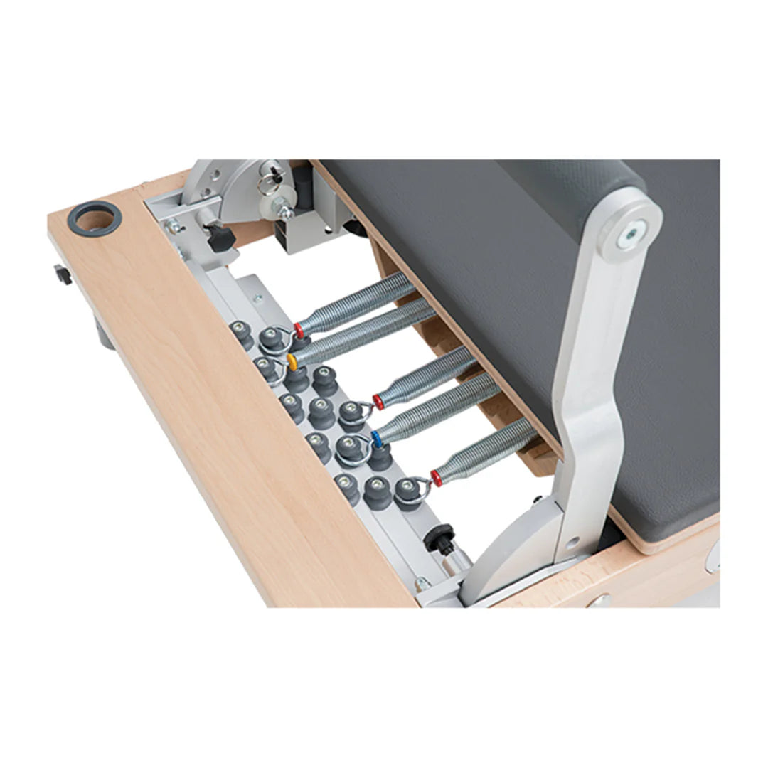 Close-up of the BASI Systems Reformer Combo's spring-loaded pulley system with wooden push-through bar and adjustable tower frame used for Pilates exercises.