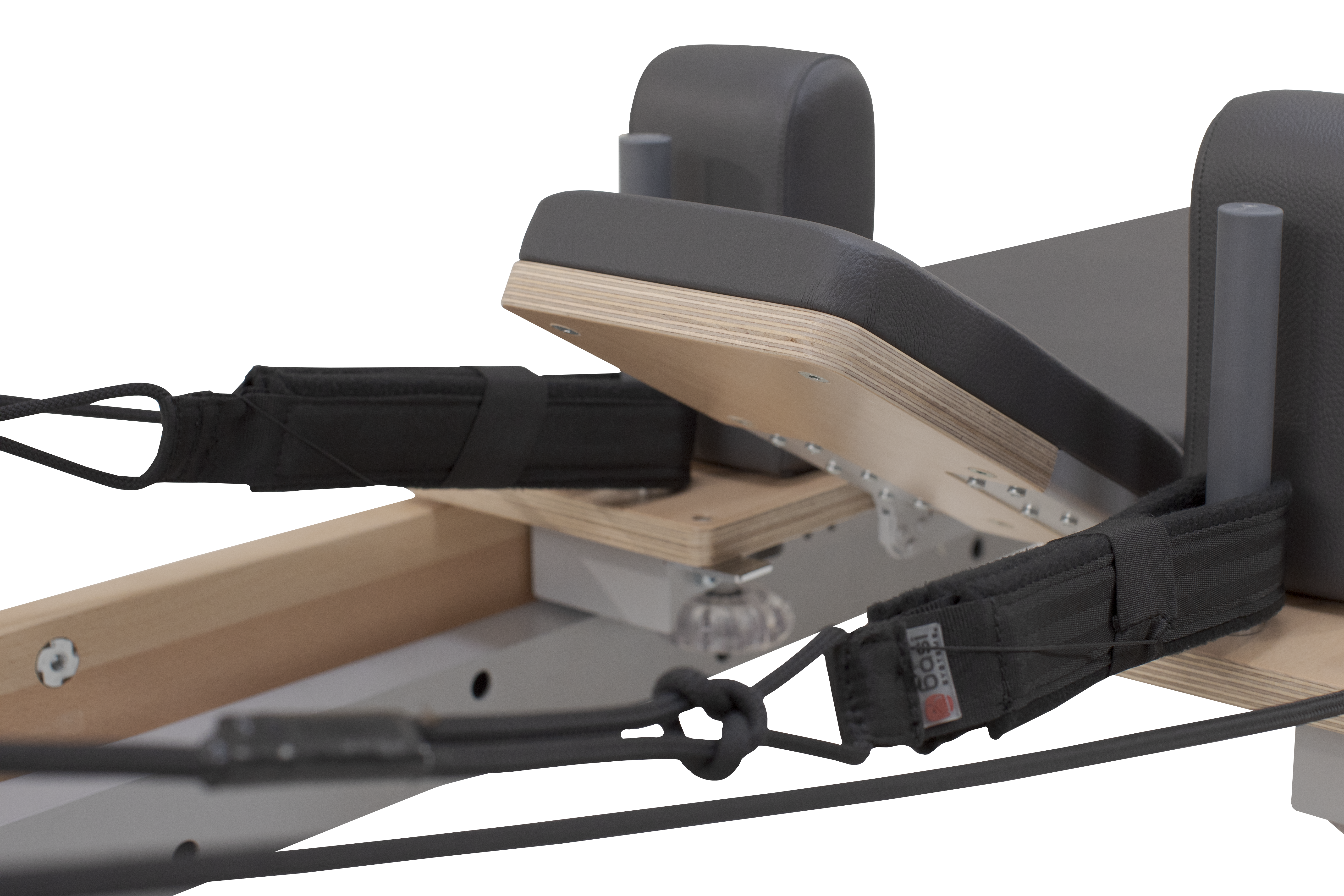 Adjustable padded headrest and shoulder blocks with straps on a professional Pilates reformer machine frame.