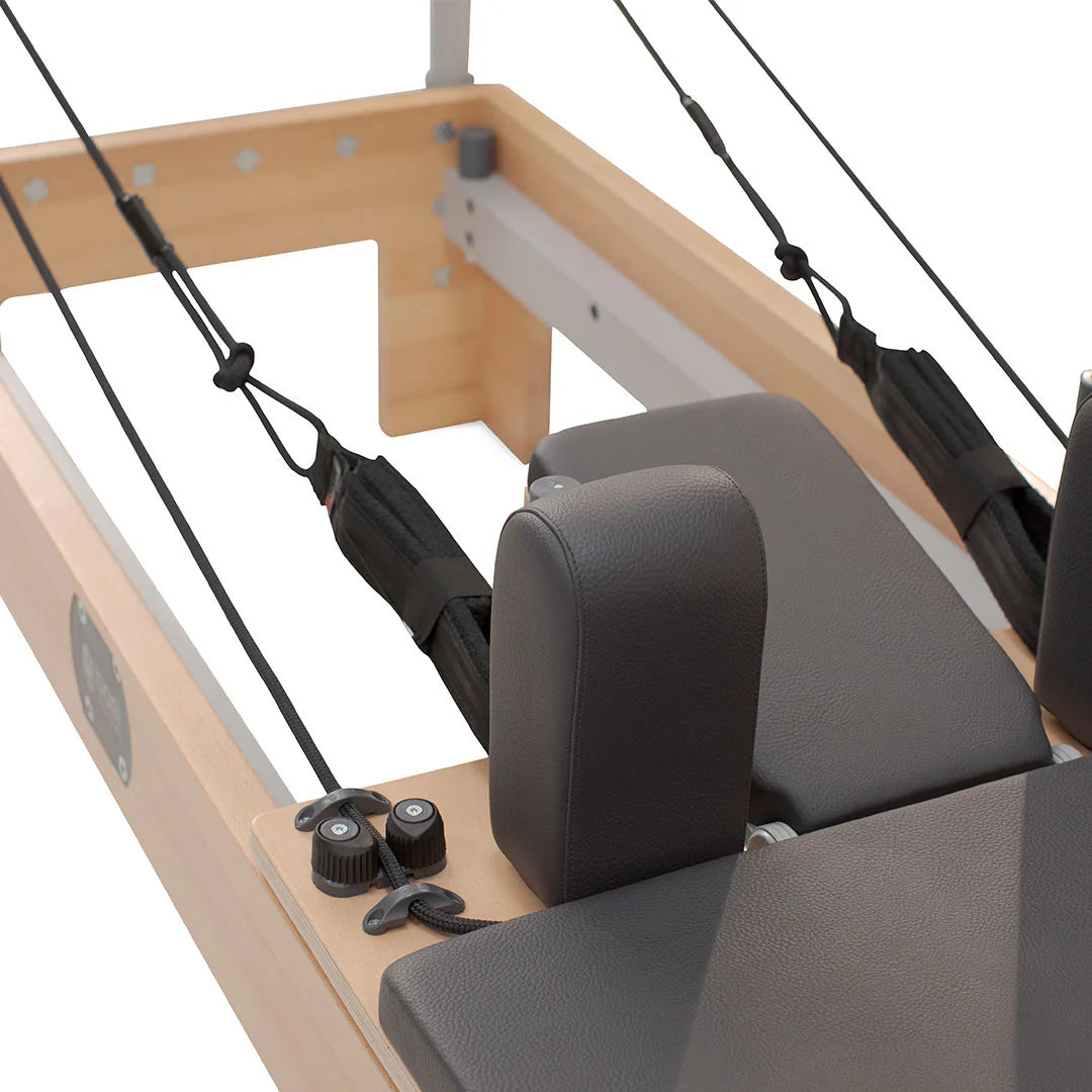 Close-up view of foot straps, headrest, and padded carriage on a professional Pilates reformer machine.