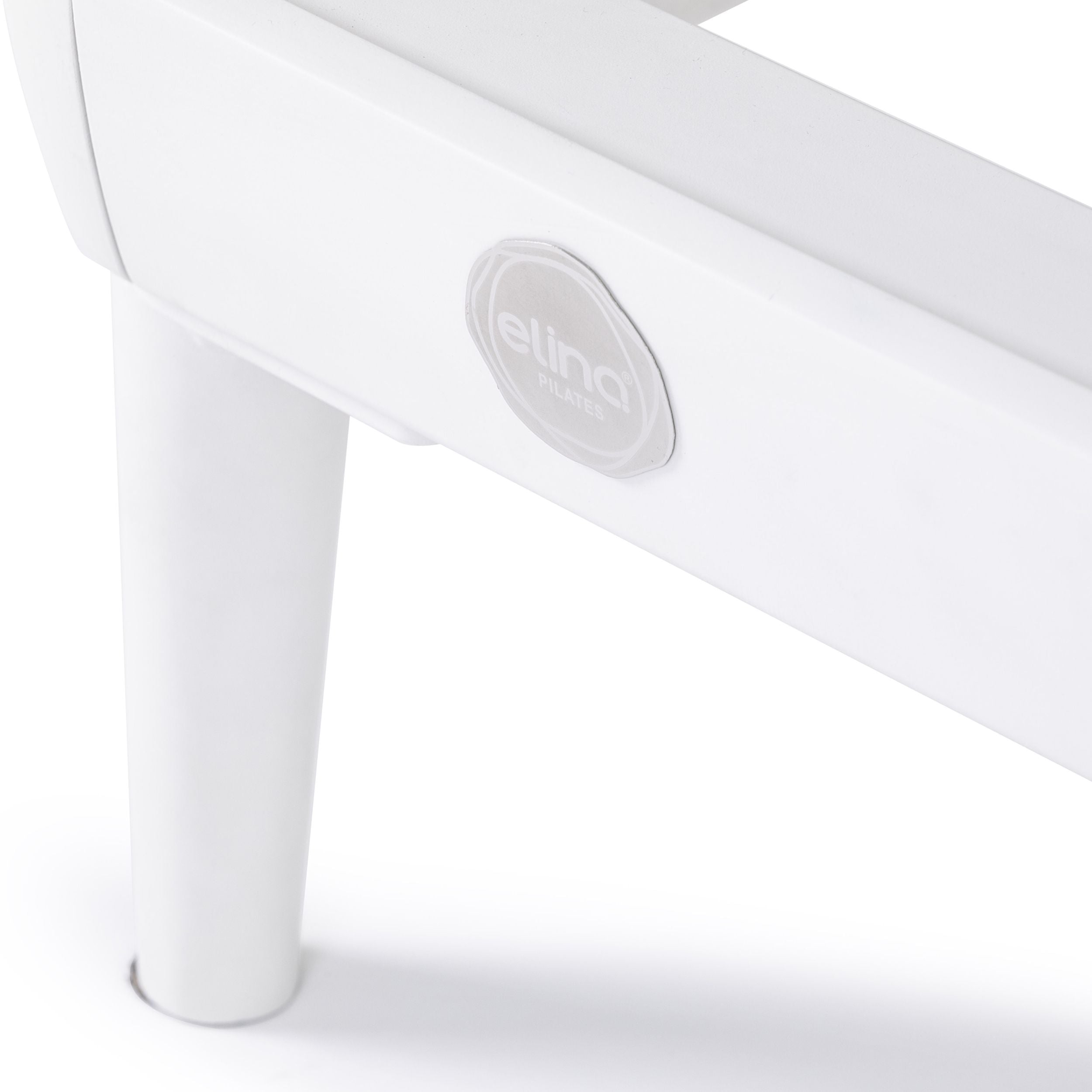 A pilates reformer featuring a padded seat and adjustable footrest for various exercises.