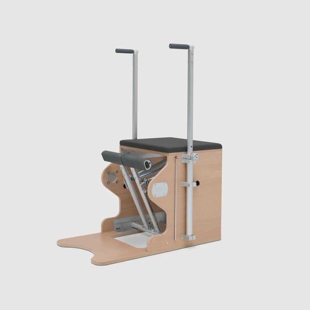 Pilates Wunda Chair with split pedals, handles, springs, and cushioned wooden seat.