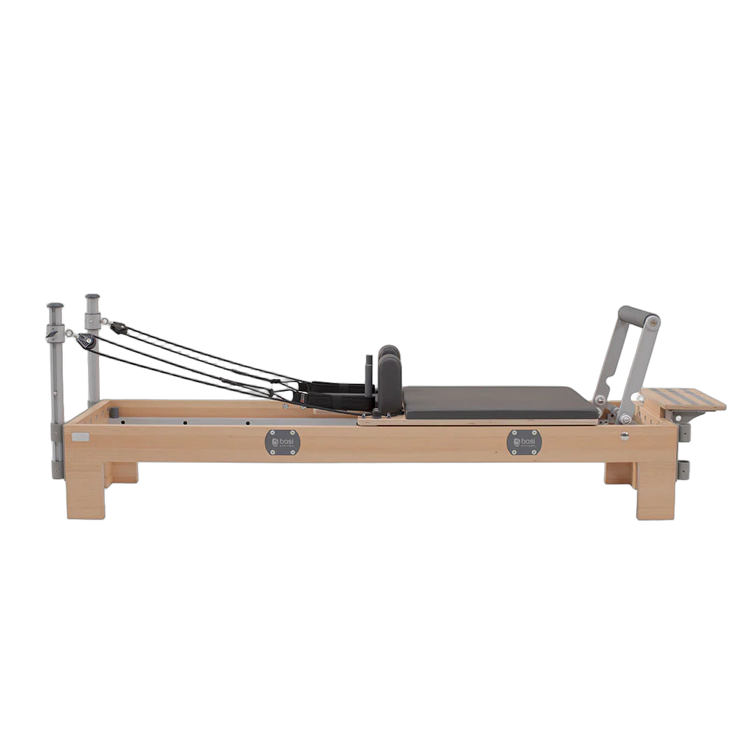 A pilates reformer featuring a padded seat and adjustable footrest for various exercises